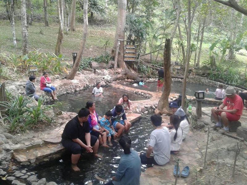 Hot Spring Relaxation at Pha Daeng National Park People relaxing in a natural hot spring surrounded by trees and rocks at Pha Daeng National Park.