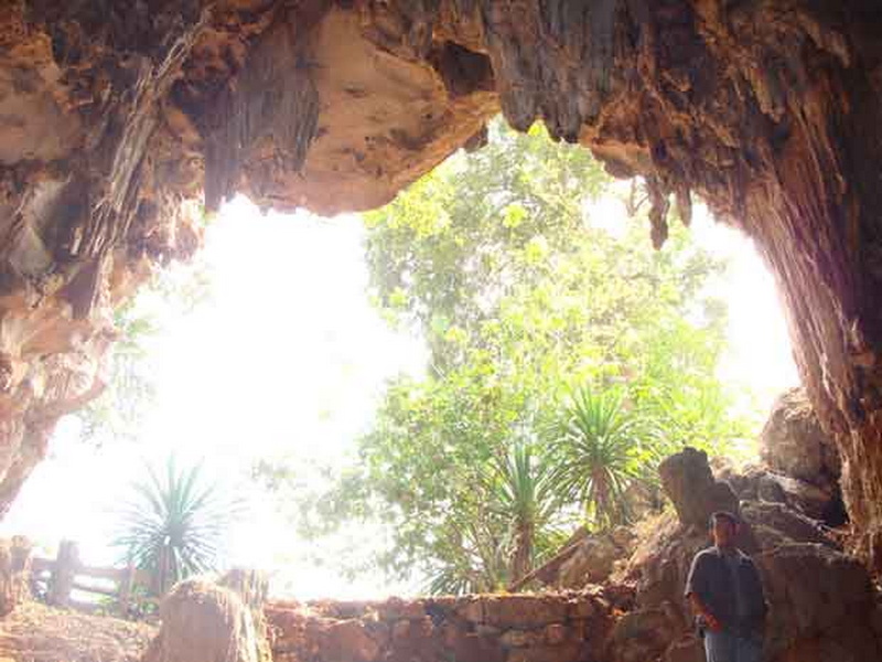 Cave Interior with Sunlight at Pha Daeng National Park Person standing inside a rocky cave with sunlight and greenery outside at Pha Daeng National Park.