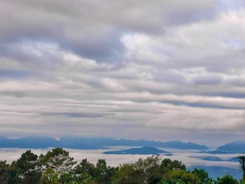 Overcast sky with clouds above a forested area and distant mountains at Si Lanna National Park.