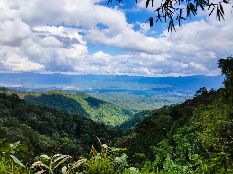 Scenic view of green hills and mountains beneath a partly cloudy sky at Si Lanna National Park.