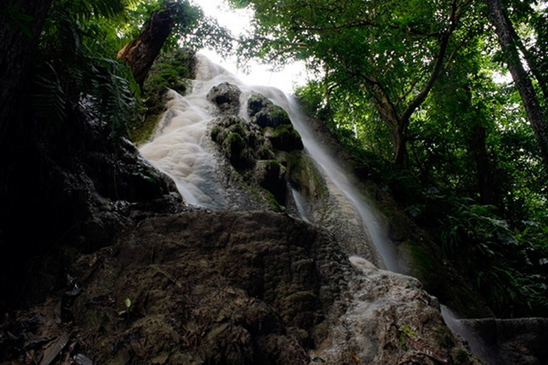 Serene Forest Waterfall at Sri Lanna National Park Waterfall cascading over rocks in a lush dense forest at Sri Lanna National Park.