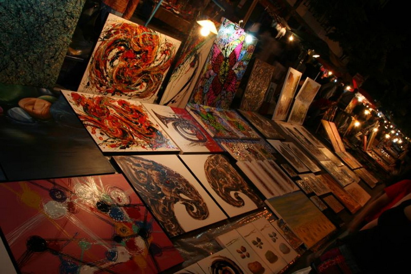 Paintings on display at an art stall during a night market scene at Best Things To Do At Night In Chiang Mai.