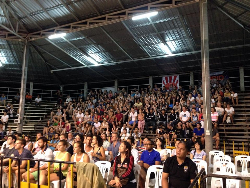 Indoor Stadium Audience at Nightlife In Chiang Mai Old City Large crowd seated inside a stadium with tiered benches and plastic chairs at Nightlife In Chiang Mai Old City.