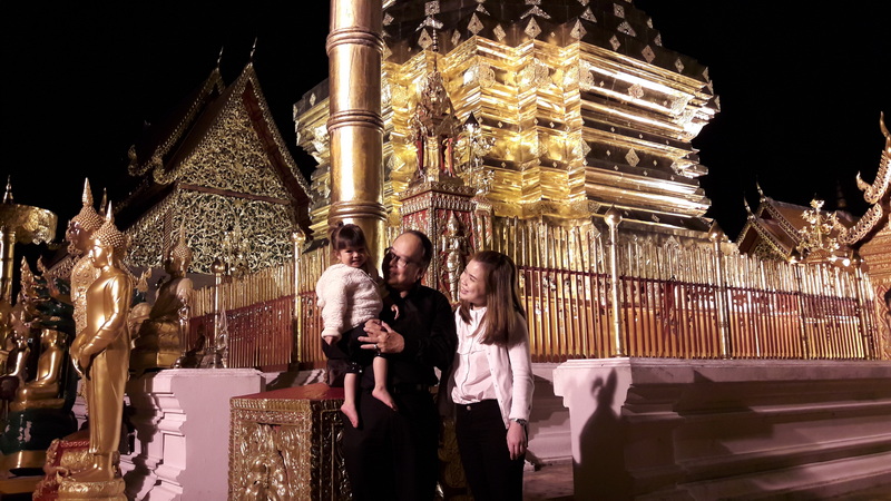 Family at Night Temple at Night Activities In Chiang Mai Family standing in front of a brightly lit golden temple at night at Night Activities In Chiang Mai.