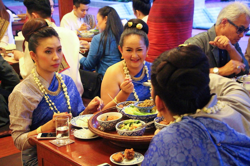 Women in traditional Thai attire enjoying dinner at a restaurant at Things to Do in Chiang Mai at Night.