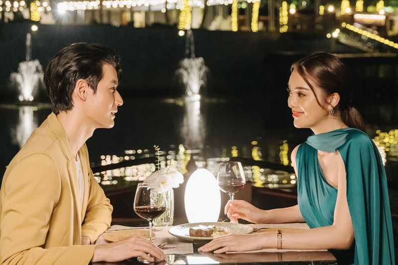 Couple enjoying dinner by the water with city lights and fountains in background at Things To Do In Chiang Mai Evening.