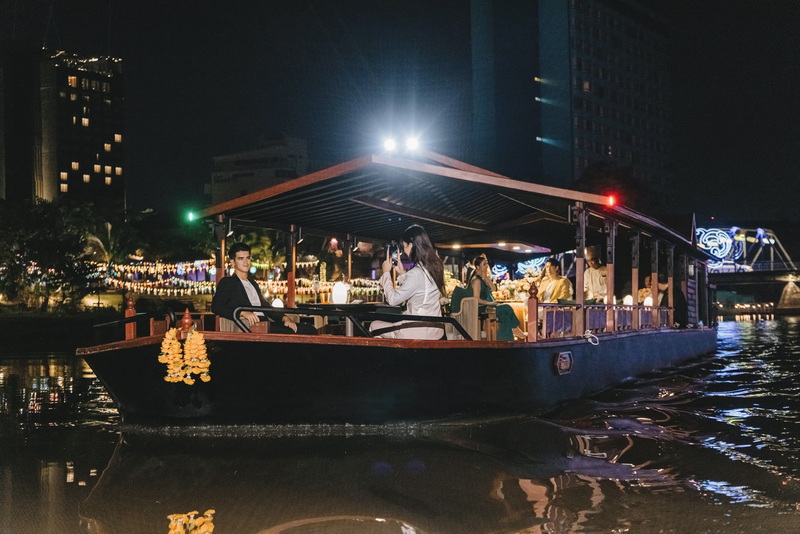 People on a boat cruising on a river with city lights at night at Night Tours In Chiang Mai.