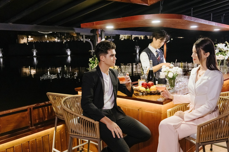 Man and woman enjoying drinks at a boat bar on water at night at Things To Do In Chiang Mai Evening.
