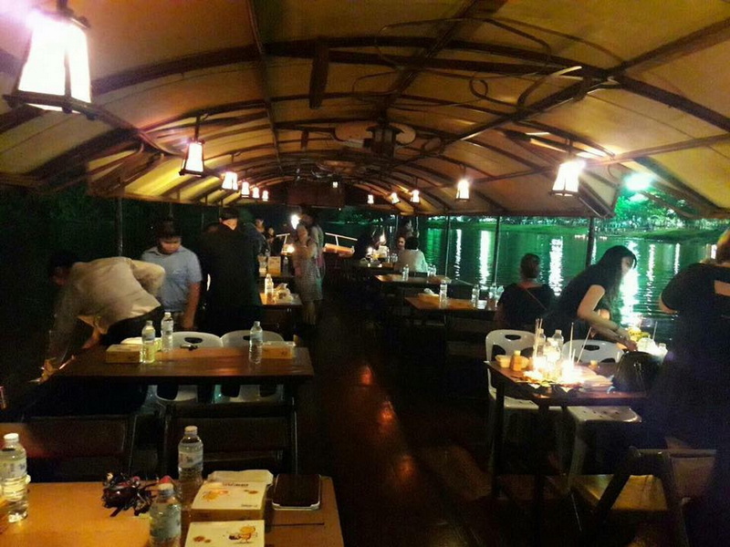 People dining on a boat with water and lights visible at night at Night Activities In Chiang Mai.