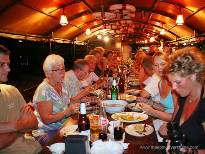 People dining together inside a warmly lit, wooden-ceiling vehicle with tableware at Nightlife In Chiang Mai Old City.