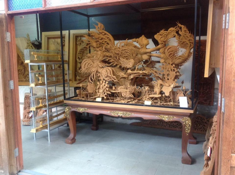 Exquisite Wooden Dragon Carving at Baan Tawai Detailed wooden carving of dragons and mythical beings displayed in a glass showcase at Baan Tawai.