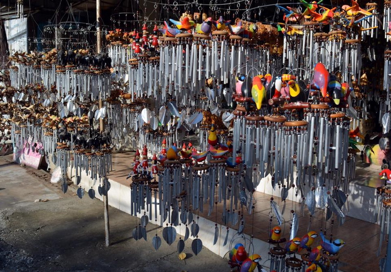 Display of colorful wind chimes and wooden mobiles hanging outdoors at Baan Tawai.