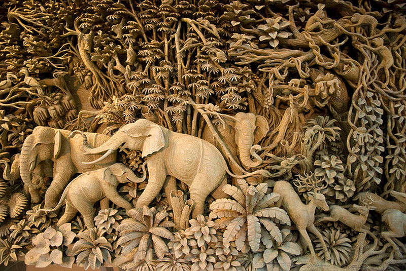 Intricate Wooden Elephant Carvings at Baan Tawai Detailed wooden sculpture featuring carved elephants and plants in natural tones at Baan Tawai.
