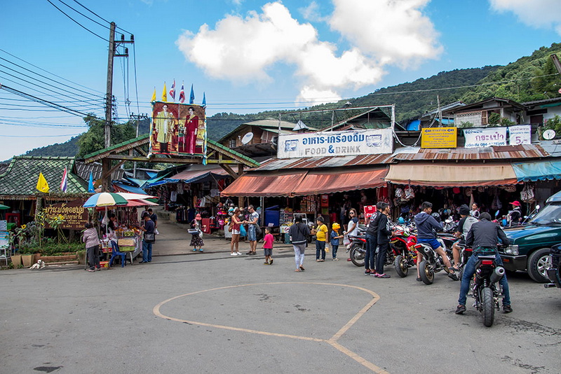 Vibrant Local Market Scene at Hmong Doi Pui Village Crowded market scene with shops, motorcycles, and visitors against a hillside backdrop at Hmong Doi Pui Village.