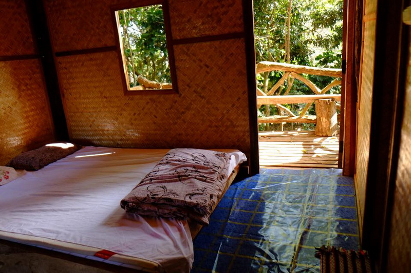 Cozy Room with Balcony View at Khun Chang Kian Village Simple bedroom with a bed and open balcony door showing green trees outside at Khun Chang Kian Village.