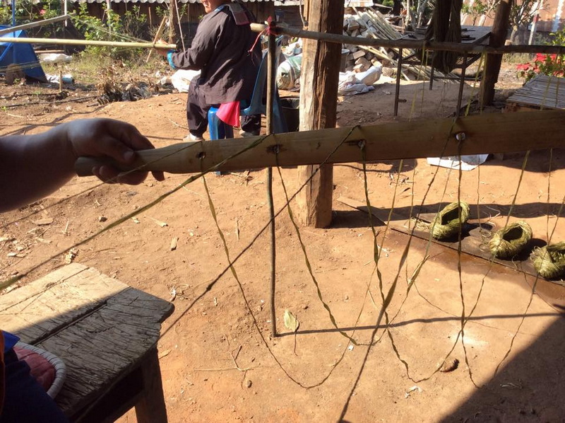 Homemade Slingshot in Outdoor Setting at Khun Chang Kian Village Person holding a handmade wooden slingshot in an outdoor area with dirt ground and background objects at Khun Chang Kian Village.