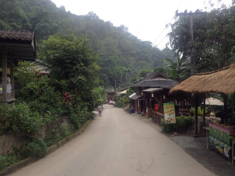 Village Street Scene at Mae Kanpong Village Dirt road with small houses and shops among lush greenery and hills at Mae Kanpong Village.