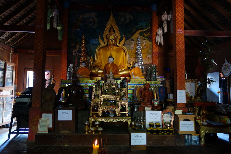 Inside temple with large golden Buddha statue and ornate decorations at Ban Mae Kanpong.