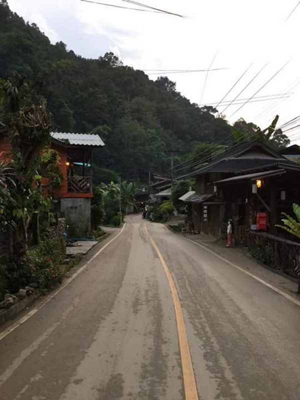 Scenic Village Road at Mae Kanpong Village Winding village road with houses and green hills in the background at Mae Kanpong Village.