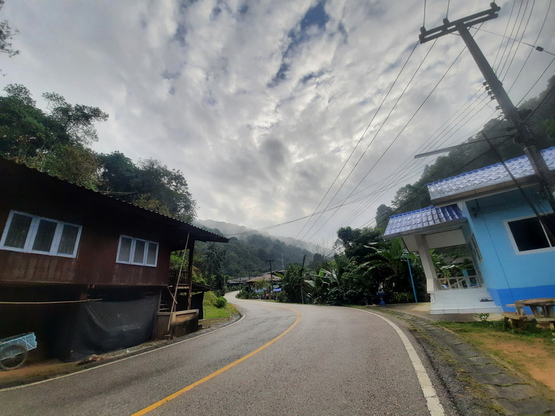 Scenic Rural Road Scene at Pang Hi Village A rural road with houses, trees, and clouds overhead in a hilly area at Pang Hi Village.