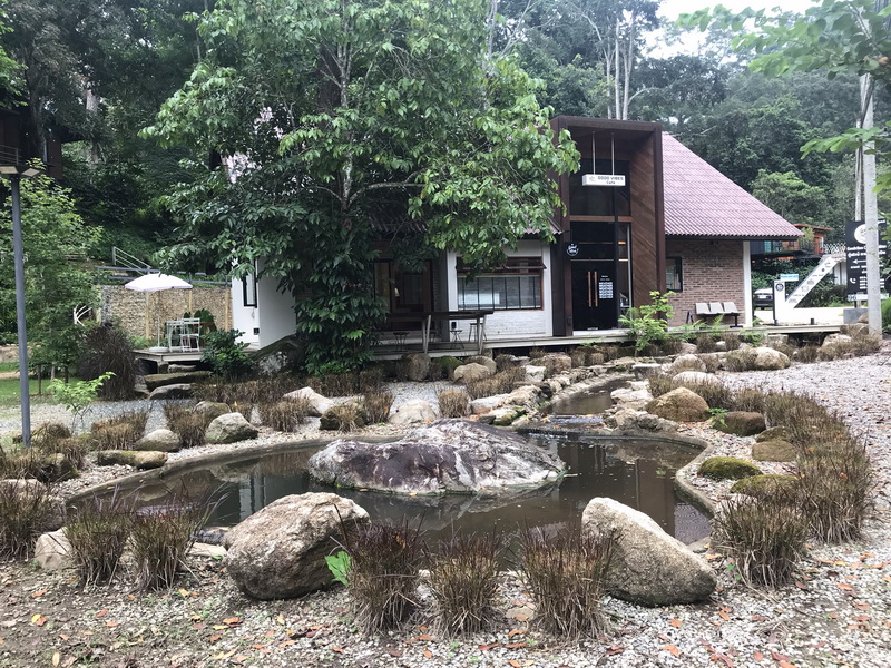 Modern building next to a pond with rocks and lush trees around at Pang Hi Village.