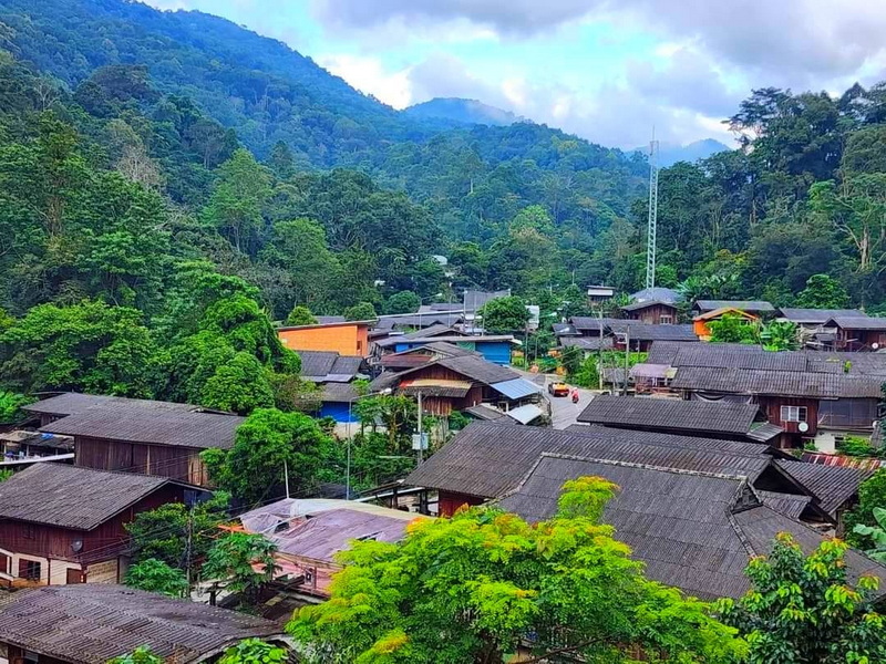 Village Amidst Forested Hills at Pang Hi Village View of a village with wooden houses amidst green trees and forested hills at Pang Hi Village.