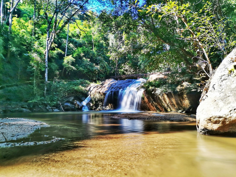 Serene Forest Waterfall at Mae Sa Waterfall Small waterfall flowing into a tranquil stream amid lush green forest at Mae Sa Waterfall.