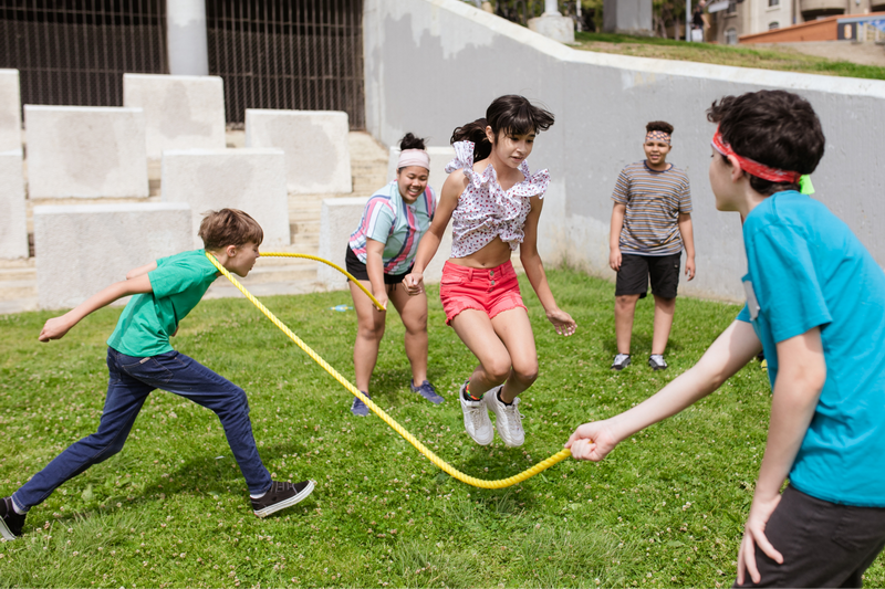 Children Playing Jump Rope at Summer Camp In Chiang Mai Children playing jump rope outdoors on grass in a courtyard at Summer Camp In Chiang Mai.