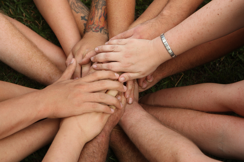 Hands in a Circle at Teenager Camps Chiang Mai Group of hands overlapping in a circle on grass outdoors at Teenager Camps Chiang Mai.