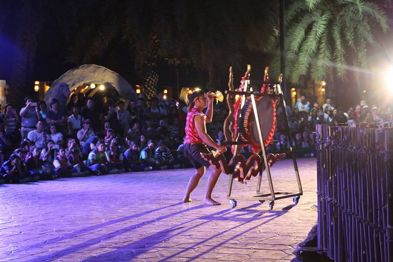 Girl dancing in front of audience outdoors at night with lights and trees at Chiang Mai Night Safari.